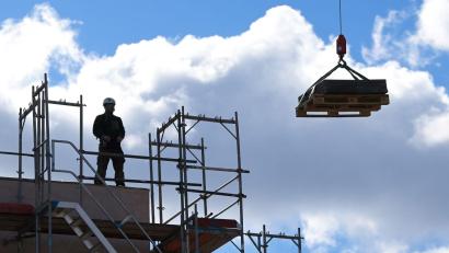 Bild: Soeren Stache/dpa-Zentralbild/dpa/Archivbild
Ein Arbeiter dirigiert auf einer Baustelle einen Kran. Die Saison in den Außenberufen beginnt wieder. Das macht sich bei den Arbeitslosenzahlen bemerkbar.