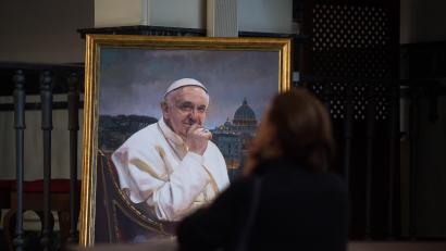 Symbolbild: Jesus Merida/dpa
Eine Frau betet zu der Jungfrau neben einem Gemälde des verstorbenen Papstes Franziskus.