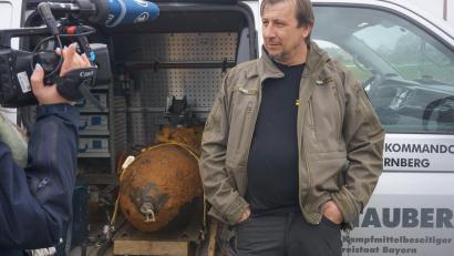 Bild: jut
Lässig neben der Bombe: Nach getaner Arbeit beantwortet Sprengmeister Michael Weiß die Fragen der Pressevertreter. Zuvor hatte er eine 450-Kilo-Fliegerbombe in Amberg entschärft – unter besonderen Umständen.