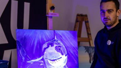 Bild: lum
David Frischholz präsentiert ein Bild, das im Rahmen der vergangenen Ausstellung „Unterwasserwelten“ mit fluoreszierenden Farben entstanden ist.