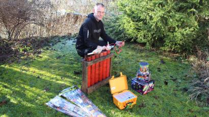 Bild: Jennifer Battaglia
Der "Pyrohase" in Aktion: Pyrotechniker Armin Hase mit explosiven Materialien in seinem Garten. In der Hand hält der Feuerwerker eine Kugelbombe, die durch ein Bombenrohr in den Himmel geschossen wird. Der kleine gelbe Koffer davor ist eine Funkzündanlage. Rechts und links daneben liegen freiverkäufliche Kleinfeuerwerke.