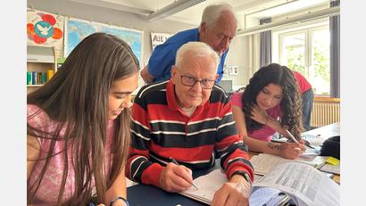Bild: Veit Wagner, Ak Asyl
Dieter Bock (vorne, Mitte) und sein Kollege Karl-Heinz Schmidkonz (hinten) beantworten ihren Schülerinnen Fragen zu den Mathe- und Physik-Hausaufgaben.