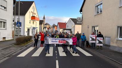Bild: knh
Anlieger der Hüttener Straße und Mitglieder der Bürgerinitiative „Umgehungsstraße Mantel – jetzt!“ bremsten den Verkehrsfluss am Zebrastreifen beim Gasthaus „Hauptmann“ und machten auf die Forderung nach einer Umgehungsstraße aufmerksam.