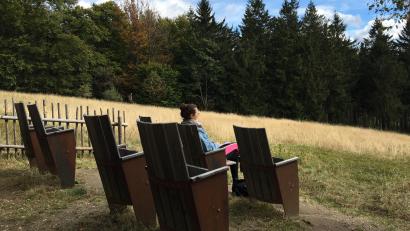 Bild: Maximilian Hohlheimer
Sieben hölzerne Klappstühle, die an Kinosessel erinnern, laden Wanderer ein, den Ausblick über die Waldlandschaft des Böhmerwalds zu genießen.