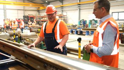 Bild: Hirsch
Qualitätsprüfer Korbinian Fütterer (links) und Werkleiter Christian Suhren (rechts) erklären die Funktion des Herzstückes einer Weiche. Von diesen werden im Schwellenwerk Schwandorf aktuell 300 Stück im Jahr hergestellt. Nach dem Endausbau sollen es 800 sein.