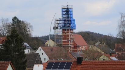 Bild: ds
Umgeben von einer Schutzplane erneuern Fachkräfte die schadhaften Gebälkteile an der Turmspitze von St. Nikolaus in Etzelwang.