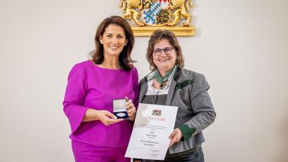 Bild: Alexander Göttert/StMELF 
Ministerin Michaela Kaniber (links) überreicht die Staatsmedaille in Silber an Erika Sauer.