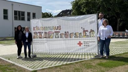 Bild: Angela Burger
Von links: Bürgermeisterin Margit Bayer, Einrichtungsleitung Alice Hübsch, BRK-Kreisgeschäftsführer Sven Lehner und stellvertretende Einrichtungsleitung Kathrin Götzl präsentieren den Namen und das Logo der neuen BRK-Kindertageseinrichtung.