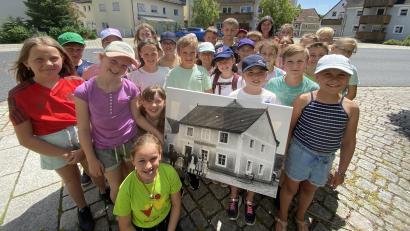 Bild: Ina Piehler
Die Kinder der Grundschule Freudenberg vor dem Gasthaus Dotzler, dem "Romwirt". Sie haben ein Bild dabei, das das "Gasthaus zum schwarzen Raben" vor über 100 Jahren zeigt.