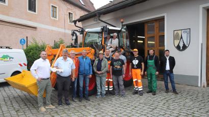Bild: war
Der neue Kommunaltraktor in oranger Lackierung vor dem Etzenrichter Bauhof. Bürgermeister, Gemeinderäte, Bauhofmitarbeiter und Verantwortliche des Lieferanten Baywa stellen sich zum Fototermin am Tag der „offiziellen Übergabe“ des neuen Kommunalfahrzeuges auf.