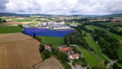 Bild: rw
Um rund sechs Hektar (blaue Fläche) soll das Gewerbegebiet nach Westen erweitert werden. Zwischen dem Inglashof (im Vordergrund) und dem bestehenden Gewerbegebiet liegt in der geplanten Erweiterungsfläche ein Grundstück mit verbrieftem Wasserrecht – zentraler Streitpunkt in der aktuellen Diskussion.
