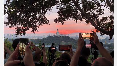 Bild: Xing Guangli/XinHua/dpa
Touristen fotografieren mit ihren Handys den farbenfrohen Sonnenuntergang über der chinesischen Hauptstadt.