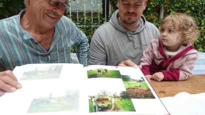 Bild: Uwe Ibl
Der Störnsteiner Schnapsbrenner Wolfgang Kriechenbauer schaut sich mit Sohn Hannes und Enkelin Neele im Fotoalbum die Bilder von der Pflanzaktion für die neue Streuobstwiese an.