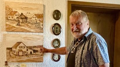 Bild: Gerhard Krones
Hartmut Schendzielorz zeigt auf sein Elternhaus in der ehemaligen Bergwerkssiedlung "Auf der Kolonie", darüber ein Bild mit dem dazugehörigen "Badhaus". Gemalt hat diese Bilder sein Schulfreund Alfred Ollek.