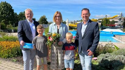 Bild: Andreas Hofmeister/Stadt Schwandorf
Oberbürgermeister Andreas Feller (links) und Bäderleiter Michael Maget (rechts) überreichen Familie Schatz aus Stulln als 100.000. Besucher der Saison eine Familienkarte für 2026.