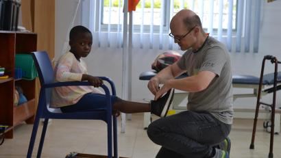 Bild:  Tonny Ssebwende/Pro Uganda
Andreas Schlang passt einem Mädchen in Uganda den Schuh an.