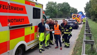 Bild: -/Branddirektion München/dpa
Die Einsatzkräfte gratulierten noch vor Ort. Der Vater (Mitte) hatte auf der A95 als Geburtshelfer tätig werden müssen.