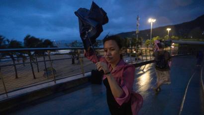 Bild: Ng Han Guan/AP/dpa
Eine Frau versucht, nach dem Super-Taifun Ragasa in Shenzhen in der südchinesischen Provinz Guangdong einen Regenschirm im Wind zu öffnen.