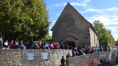Bild: bö
Pulsierendes Leben am Dorfplatz in Lutzmannstein. Viele der Teilnehmer des Heimattreffens in Lutzmannstein haben keinen Platz mehr in der ehemaligen Pfarrkirche bekommen. Sie scharten sich um die Friedhofsmauer und den Treppenaufgang zur Dorfkirche St. Maria und Sankt Luzia.