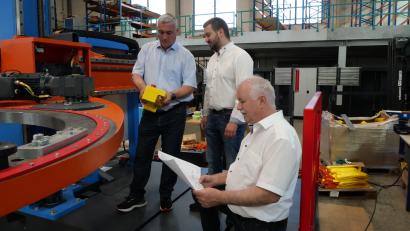 Bild: Julia Benkhardt [jbe]
Rüdiger Kohls, Florian Meierhöfer und Alfons Meierhöfer (von links) an der Bandagiermaschine, die die einzelnen Säulen des stehenden Trafokerns mit einem höheren Glasfaserband umwickelt, um eine höhere Effizienz zu erzielen.