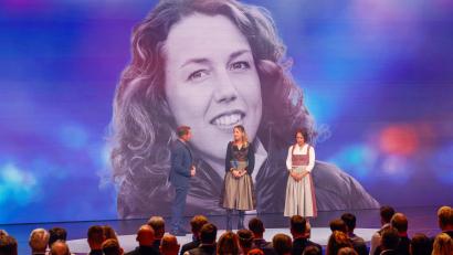 Bild: Alexandra BEIER/BayStMI/dpa
Die Biathletinnen Franziska Preuß und Magdalena Neuner (hier mir Moderator Markus Othmer vor einem Bild von Laura Dahlmeier) haben bei der Verleihung des Bayerischen Sportpreises ihrer gestorbenen Kollegin Dahlmeier gedacht.