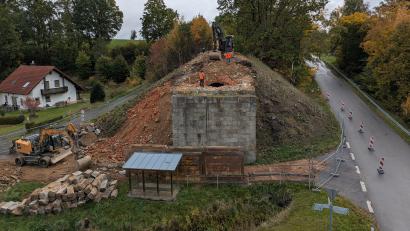 Bild: pz
Seit der ersten Oktober-Woche werden die beiden Widerlager der früheren Eisenbahnbrücke in Hundsbach abgerissen. Das Bushäuschen kann aktuell nicht benutzt werden. Zudem wird die Zufahrt zum Dorf an dieser Stelle ab 20. Oktober gesperrt.