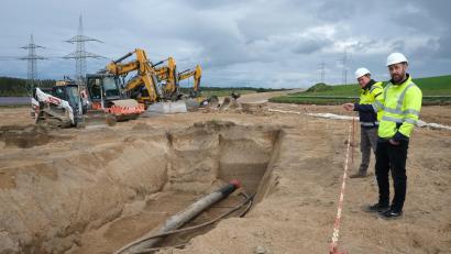 Bild: Hirsch
Mit schwerem Gerät werden 1,80 Meter tiefe Schneisen gegraben. Die TenneT-Vertreter Johannes Prechtl und Markus Lieberknecht (von rechts) erläuterten an der Baustelle bei Nittenau die Verlegung der Schutzrohre, in die später die Stromleitungen eingezogen werden.