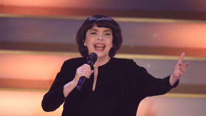 Bild: Bodo Schackow/dpa
Mit Chanel-Hut und chinesischem Sonnenschirm schützt Chanson-Legende Mireille Mathieu ihre Haut. (Archivbild)