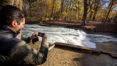 Bild: Peter Kneffel/dpa
Freizeitsurfer Alexander Neumann fotografiert die - zurzeit nicht funktionstüchtige - Eisbachwelle im Englischen Garten.