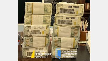 Bild: -/Nationales Antikorruptionsbüro der Ukraine/Spezialisierte Antikorruptionsstaatsanwaltschaft der Ukraine/dpa
Druckfrische originalverpackte Dollar-Bündel werden in der Ukraine für Schmiergeldzahlungen verwendet.