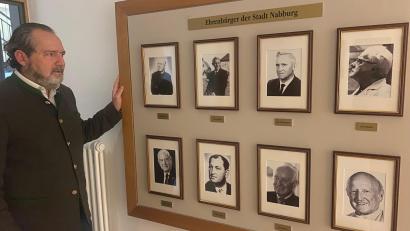 Bild: jua
Die acht Ehrenbürger der Stadt Nabburg sind nun sichtbar im Rathaus verewigt. Bürgermeister Frank Zeitler (links) zeigt die Neu-Installation.