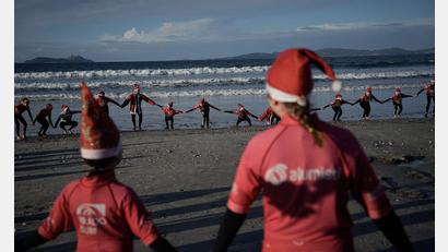 Bild: Adrián Irago/EUROPA PRESS/dpa
Mit Weihnachtsmannmützen verkleidete Menschen surfen während der „Papanoelada Surfera“ (Surfer-Nikolaus-Aktion) am Strand von Patos.