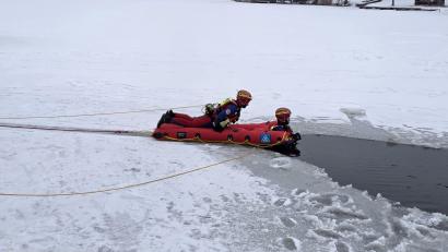 Bild: Josef Ott
Ein Wasserretter kommt mit einem Eisrettungsschlitten einer im Eis eingebrochenen Person zu Hilfe. Der Schlitten und der Wasserretter sind durch ein Seil gesichert. Während der Übung auf dem Rußweiher in Eschenbach war auch die eingebrochene Person vom Ufer aus durch ein Seil abgesichert.