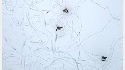 Bild: Helmut Fohringer/APA/dpa
Muster im Schnee: Eine Luftaufnahme zeigt Schlittschuhläufer auf einem zugefrorenen See in Österreich.