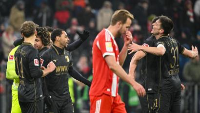 Bild: Peter Kneffel/dpa
Die Spieler des FC Augsburg jubeln nach Spielende. Bayerns Harry Kane (rotes Trikot) ist frustriert. Die Münchener verloren mit 1:2.