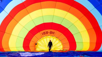 Bild: Cyril Zingaro/KEYSTONE/dpa
Ein Teammitglied überprüft seinen Heißluftballon vor dem Start während des 46. Internationalen Heißluftballon-Festivals in Chateau-d'Oex.