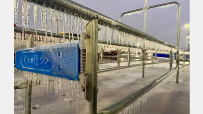 Bild: John Raby/AP/dpa
Eiszapfen hängen an einem Geländer während eines Wintersturms auf einem Parkplatz.