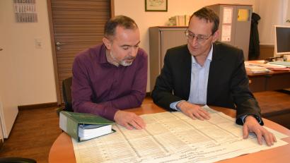 Bild: as
Bei Kreiswahlleiter Markus Zapf (rechts) und seinem Stellvertreter Thomas Schraml laufen die Fäden der Organisation zusammen. Ähnlich groß wie der Stimmzettel zur Kreistagswahl 2020, den sie hier zu Vergleichszwecken vor sich ausgebreitet haben, wird auch die Liste im März 2026 sein. Statt sieben Listen gibt es diesmal acht.