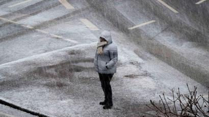Bild: Boris Roessler/dpa
Eine Person steht bei starkem Schneefall an einer Kreuzung in Frankfurt.