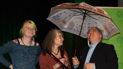 Bild: mfh
Ein Regenschirm, den Elli Wolf und Yvonne Rösel (von links) Stefan Schmidt überreichten, soll den Bundestagsabgeordneten von Bündnis90/Die Grünen "vor den Tränen des Bundeskanzlers schützen, falls die Grünen bei der Kommunalwahl als Gewinner hervorgehen".