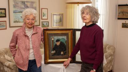 Bild: Thomas Sporrer
Gunda Eckert (links) und Annemarie Doyscher mit dem Originalbild von Pater Benedikt Üblacker. Überraschung: Es ist farbig. Laut Annemarie Doyscher gibt es die Standuhr auf dem Bild hinten links immer noch, sie wird nach wie vor in Ehren gehalten.