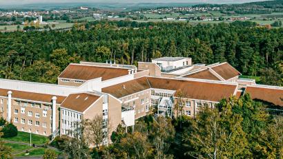 Bild: Asklepios-Klinik/exb
Zwischen Bäumen eingebettet liegt die Asklepios-Klinik Lindenlohe bei Schwandorf, die sich auf orthopädische Behandlungen und Operationen spezialisiert hat. Sie existiert seit 75 Jahren und ist seit zwei Jahrzehnten Teil der Asklepios-Gruppe. Im Hintergrund sieht man Schwarzenfeld (links) und die Kirche auf dem Miesberg.
