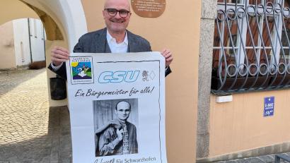 Bild: ihl
Maximilian Beer vor dem Rathaus in Schwarzhofen, in dem er sechs weitere Jahre der Chef ist. Er hat sein allererstes Wahlplakat von 1996 hervorgeholt. Das locker über der Schulter hängende Jackerl gefällt damals nicht jedem.