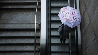 Bild: Christoph Schmidt/dpa
Eine Frau fährt mit ihrem Regenschirm eine Rolltreppe hinauf. Das Wetter soll in der Region Stuttgart in den nächsten Tagen wechselhaft bleiben.
