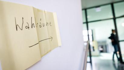 Symbolbild: Daniel Karmann/dpa
„Wahlräume“ steht auf einem Zettel als Wegweiser in einem Wahllokal in Bayern.