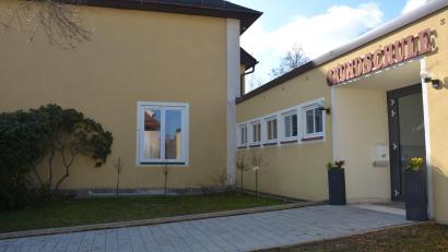 Bild: jr
Dort, wo jetzt noch ein Fenster im Rathaus ist (Hintergrund), soll bald der Hauptzugang erfolgen. Das Fenster und die Brüstung werden herausgebrochen und ein barrierefreier Zugang geschaffen. Links neben den neuem Eingang soll eine WC-Anlage gebaut werden. An Kosten rechnet die Gemeinde mit rund 100.000 Euro. Rechts ist der der Haupteingang zur Grundschule zu sehen.