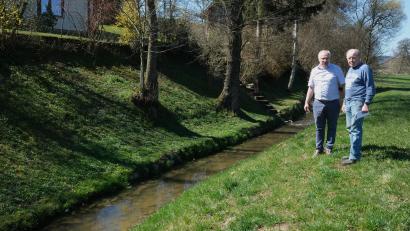 Bild: Hirsch
Laurenz Lorenz (rechts) und sein Nachbar Wolfgang Schart (links) stehen an der Böschung, die vom Wasser unterspült worden war und nachgegeben hatte. Der Auerbach fließt idyllisch vorbei. Doch in Zeiten der Schneeschmelze tritt er über die Ufer.