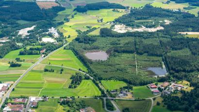 Luftbild: René Mühlmeier
Südlich und östlich des Engelmannsteichs (Bildmitte) hätte nach den Plänen der mittlerweile insolventen Ziegler-Holding auf einer 37 Hektar großen Fläche an der B 15 ein Gewerbegebiet entstehen sollen. Vorgesehen war eine "Giga-Factory", ein riesiges Werk zur Produktion ökologischer Fertighäuser samt Holz-Kompetenzzentrum und Musterhaussiedlung. Der Stadtrat hat das Vorhaben nun endgültig beendet und südlich der Rothenbürger Straße, südlich des Möbelhauses Gleißner sowie östlich des Engelmannsteichs drei neue potenzielle Flächen mit insgesamt rund 30 Hektar für Gewerbeansiedlungen bestimmt.