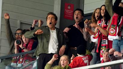 Bild: Martin Rickett/PA Wire/dpa
Die Clubinhaber Ryan Reynolds und Rob Mac gelten als leidenschaftliche Fans und sind regelmäßig bei den Spielen des AFC Wrexham. (Archivbild)