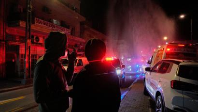 Bild: Maya Levin/AP/dpa
Anwohner beobachten die Arbeit der Rettungskräfte am Ort eines Raketeneinschlags in Tel Aviv.